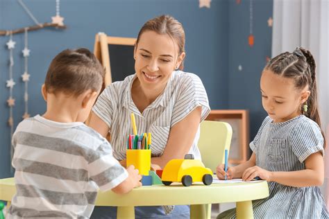 Foto de una cuidadora de niños interactuando felizmente con infantes o niños pequeños