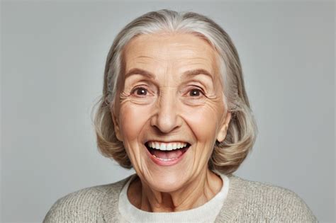 Mujer mayor sonriendo con una blusa gris claro de manga corta en un entorno veraniego