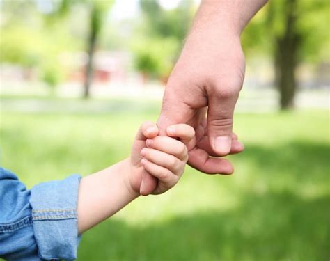 Manos de un adulto y un niño tomándose mutuamente