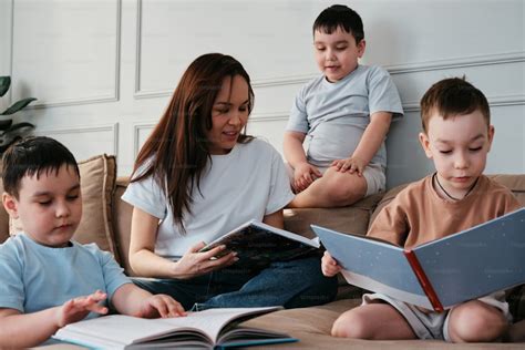 Niñera leyendo un libro a dos niños en un sofá
