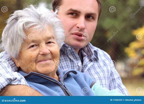 Pareja con marcada diferencia de edad, mujer mayor y hombre joven, tomados de la mano sonriendo