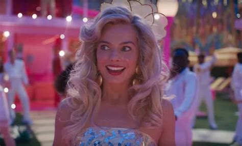 Margot Robbie como Barbie en la película, sentada en una banca junto a una anciana