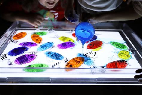 Niños jugando con materiales sensoriales en una mesa de luz
