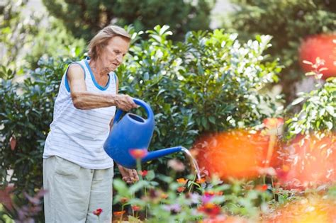 Adulto mayor regando plantas en un jardín elevado