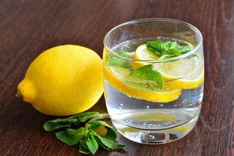 Imagen de un adulto mayor bebiendo agua con rodajas de limón y menta