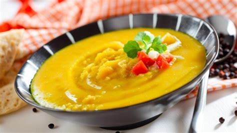 Ilustración de un puré de verduras de colores vibrantes en un cuenco, con una cuchara insertada, representando una comida apetitosa y fácil de consumir.