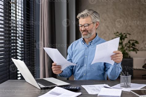 Persona mayor revisando documentos bancarios en un ordenador