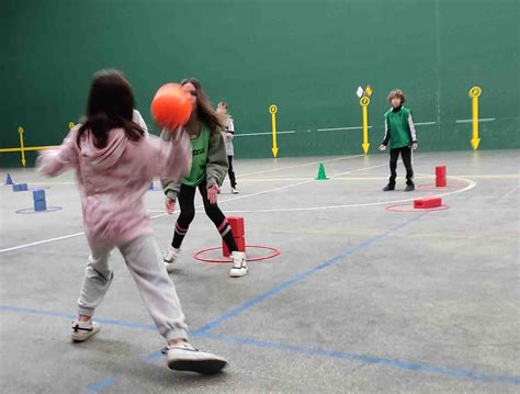 Niños participando en un juego de lanzar pelotas a través de una red.