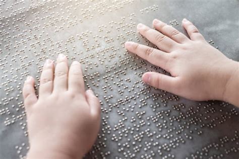 Un niño leyendo un libro en braille con la ayuda de un adulto.
