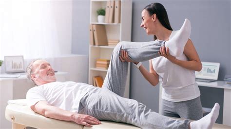 Cama clínica con adulto mayor recibiendo asistencia de fisioterapia