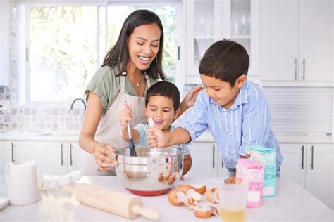 Niños cocinando juntos en la cocina, con sonrisas y utensilios adaptados