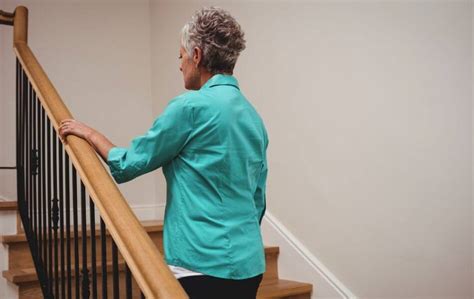 Ilustración de cómo subir a una persona mayor por escaleras usando un cinturón de seguridad y pasamanos