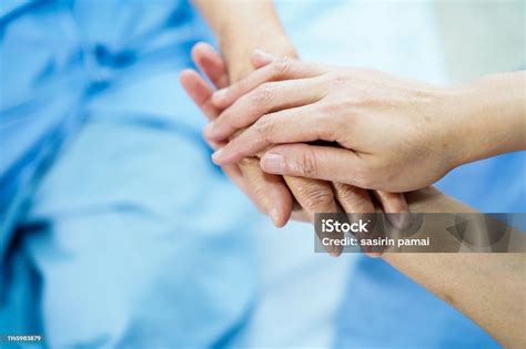 Foto de las manos de un cuidador sosteniendo las de una persona con Alzheimer