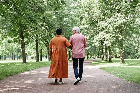 Pareja de adultos mayores caminando por un sendero arbolado.