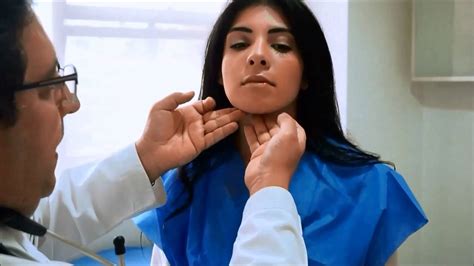 Foto de médico realizando examen físico de cabeza y cuello a un paciente mayor