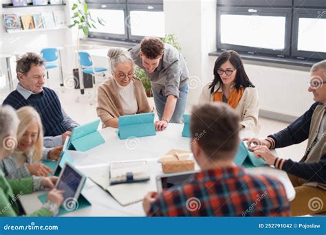 Grupo de adultos mayores utilizando tablets y computadoras en un taller