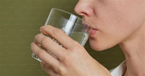 Persona mayor bebiendo con una pajita desde un vaso o botella