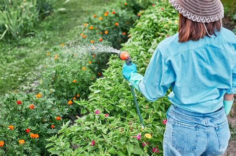 Mujer mayor regando plantas en un jardín con una sonrisa serena
