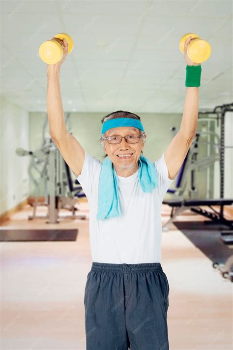 Persona mayor levantando pesas ligeras en un gimnasio supervisado