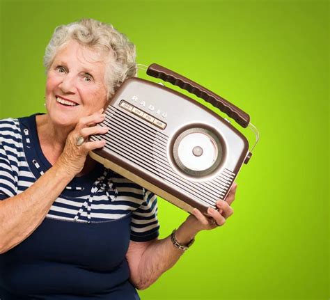 Persona mayor escuchando la radio con auriculares, sonriendo.