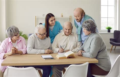 Fotografía de un grupo de ancianos socializando en una sala común con sofás y mesas adaptadas