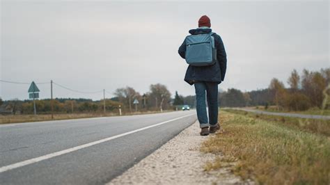 Foto temática: hombre con mochila caminando hacia una entrada de cárcel al anochecer