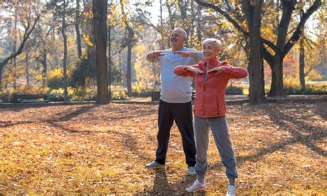 Personas mayores realizando actividades físicas suaves como caminar o yoga en un entorno al aire libre.