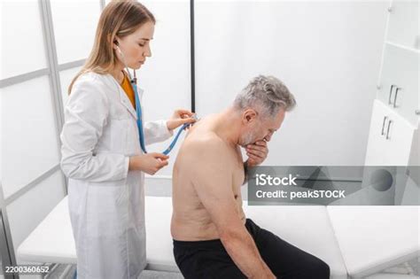 Imagen de un médico escuchando los pulmones de un paciente con un estetoscopio.