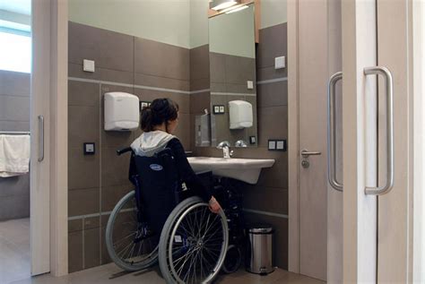 Persona en silla de ruedas utilizando un baño accesible con barras de apoyo