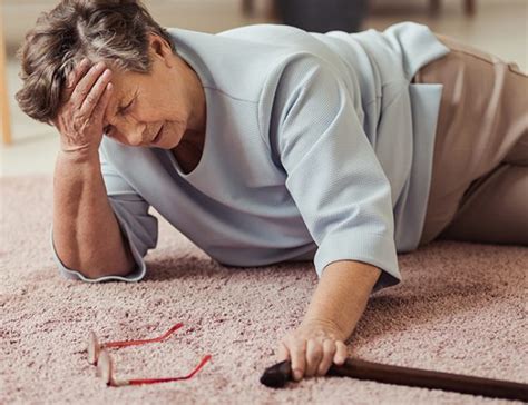 Ilustración de un hogar con varios peligros de caídas: alfombra suelta, cables en el suelo, iluminación deficiente.