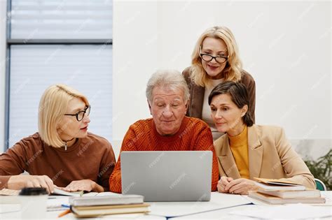 Adultos mayores aprendiendo a usar computadoras en un taller, con entusiasmo y concentración