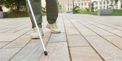 Foto: Persona con baja visión utilizando un bastón blanco en un entorno urbano accesible