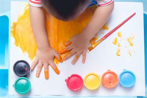Fotografía de un niño utilizando pintura de dedos sobre un papel grande para estimular su expresión sensorial.