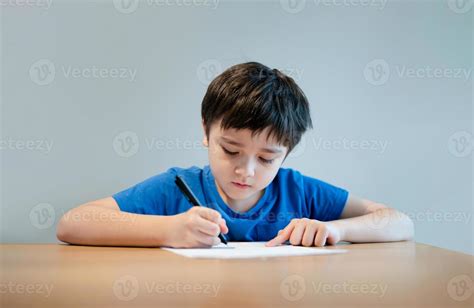 Foto de un niño concentrado escribiendo con la ayuda de un tutor