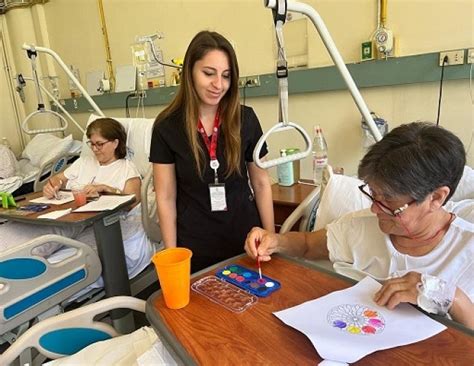 Terapeuta ocupacional interactuando con un paciente mayor en el salón de su casa, adaptando el entorno