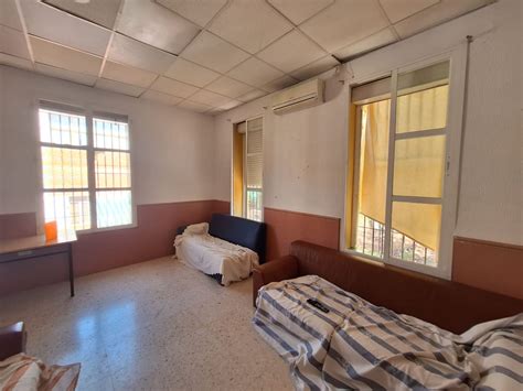 Fotografía de un centro de menores con condiciones precarias o de personal interactuando con niños en un entorno básico