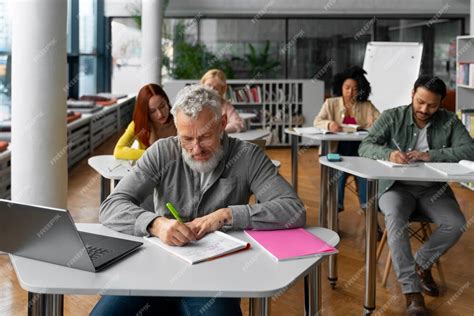 Persona mayor estudiando en una clase de adultos con otros alumnos