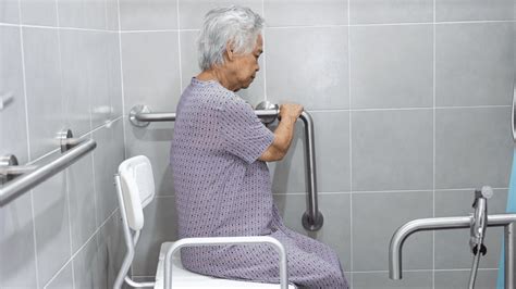 Persona mayor en la ducha con barras de apoyo