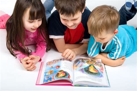 Foto de niños jugando creativamente con una niñera: haciendo manualidades o leyendo un cuento juntos