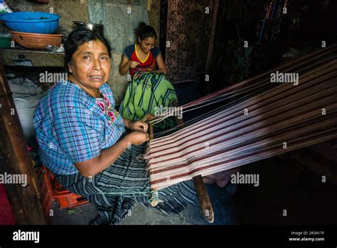 Foto de una mujer Mapuche tejiendo en un telar dentro de una ruca.