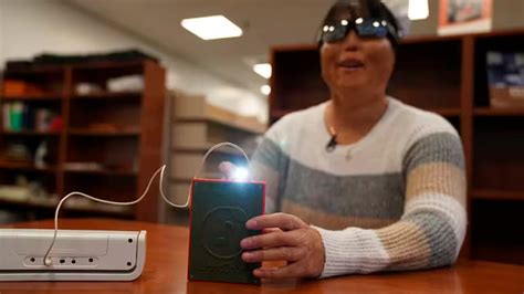 Foto de una persona con discapacidad visual probando un dispositivo LightSound en una biblioteca