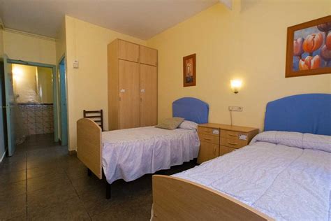 vista interior de una habitación adaptada en una residencia para mayores, con baño equipado y timbre de llamada