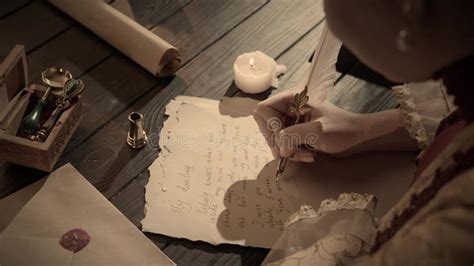 Persona escribiendo una carta con una vela encendida y una foto antigua en el fondo