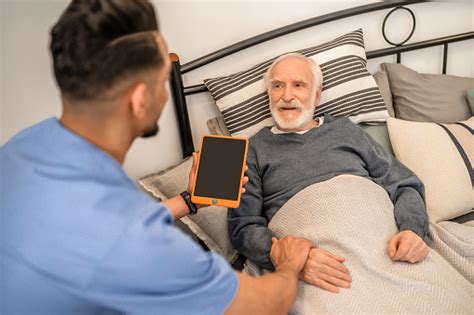 Fotografía de un hombre mayor cuidando a su padre postrado en cama.