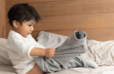 Foto de un niño en edad preescolar aprendiendo a vestirse, representando el desarrollo de habilidades adaptativas