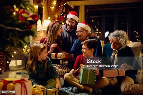 Familia multigeneracional abriendo regalos en Navidad, abuelos sonriendo