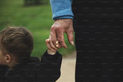 Manos de abuela sosteniendo la mano de un niño, con un fondo de cocina o jardín