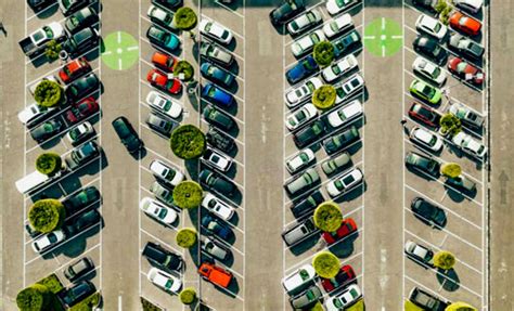 Imagen de un estacionamiento público en una ciudad, mostrando autos y personas cerca, con un enfoque en la interacción con cuidadores informales