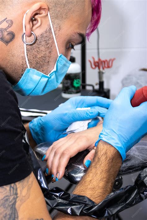 Diseñador: Ilustración detallada de un tatuador limpiando un tatuaje recién hecho en la espalda de un cliente.