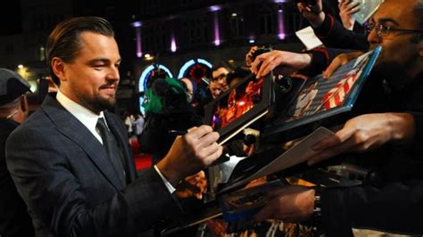 Fotografía de un futbolista famoso firmando autógrafos y camisetas para aficionados en un evento benéfico